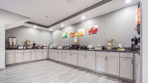 A modern kitchen with white cabinets, a marble floor, and various appliances like a coffee maker and microwave. - Quality Inn & Suites Omaha Chalco (Omaha)