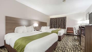 A hotel room with two beds, a desk, a chair, a television, and a patterned carpet.