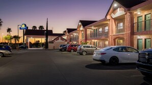 Ein Hotel mit Days Inn Schild, mehreren Balkonen und einem Parkplatz mit einigen Autos.