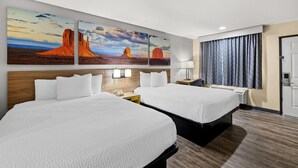 Ein Hotelzimmer mit zwei Betten, einer großen Wandmalerei, einem hölzernen Kopfteil, einem Nachttisch mit Lampe und einer Tür mit Vorhängen.
