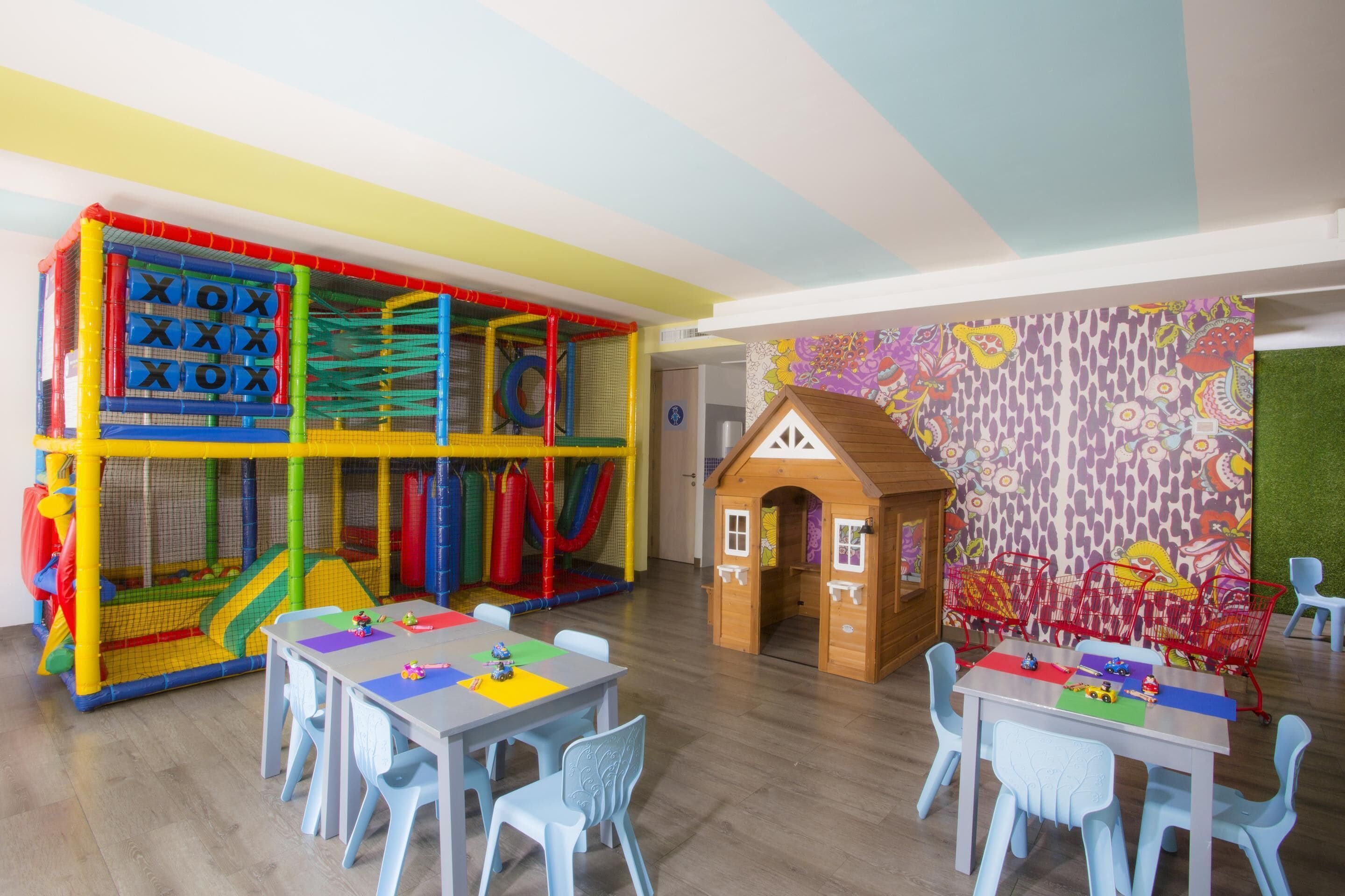 A children's play area with a climbing net, a playhouse, and a table with toys.