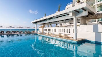 Alberca al aire libre, sombrillas en la alberca y camastros