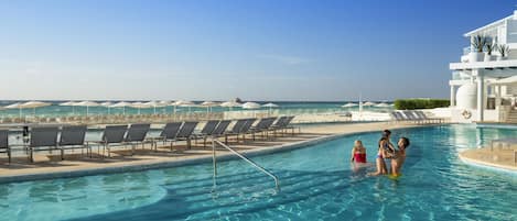 Una piscina al aire libre, sombrillas, sillones reclinables de piscina