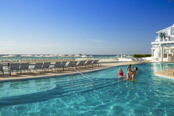 Una piscina al aire libre, sombrillas, tumbonas