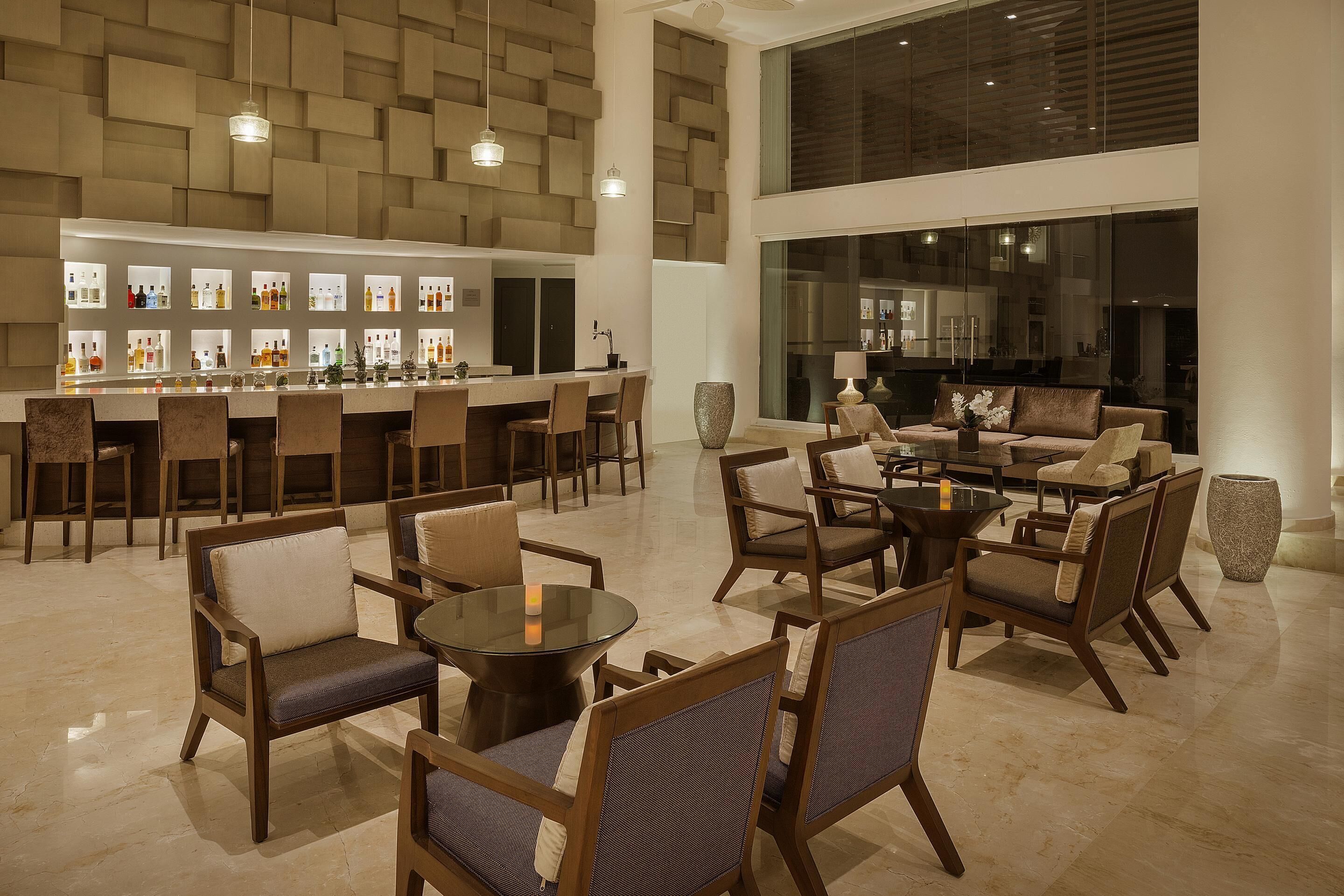 A spacious lounge area with a bar, multiple seating arrangements, and a large window providing a view of the interior.