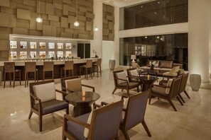 A spacious lounge area with a bar, multiple seating arrangements, and a large window providing a view of the interior.