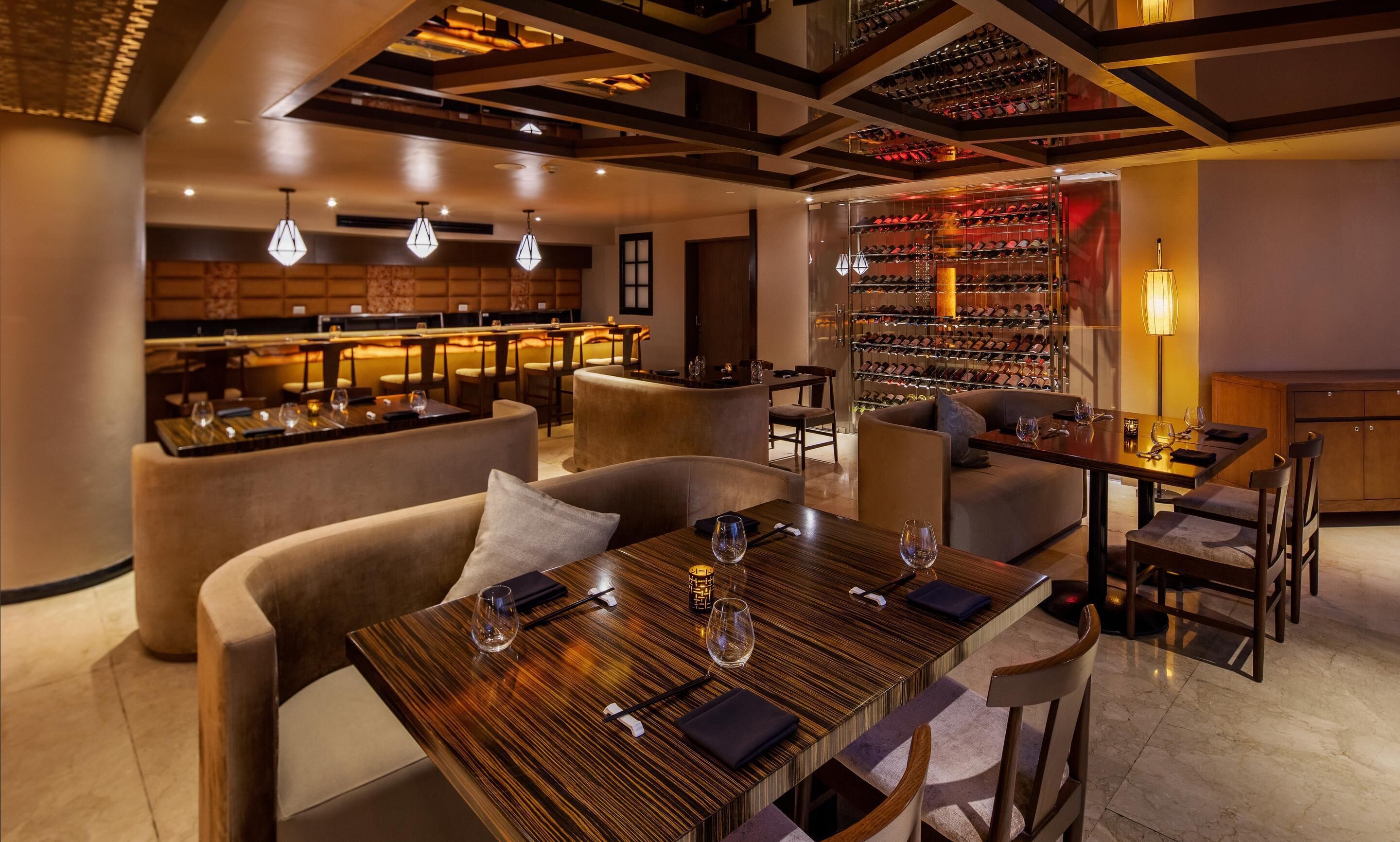 Ein modernes Restaurant mit Barbereich, Sitzgelegenheiten und einem im Hintergrund sichtbaren Weinkeller.