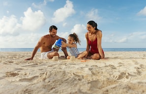 Na praia, areia branca, espreguiçadeiras, guarda-sóis 