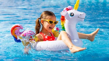 Una piscina al aire libre, sombrillas, sillones reclinables de piscina