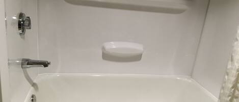 A white bathtub with a soap dish and a towel.
