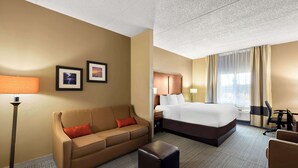 A hotel room with a bed, a sofa, a desk, and a lamp. - Comfort Inn & Suites near Kino Sports Complex (Tucson)