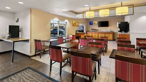 A restaurant with booths and tables, a kitchen area, and a TV on the wall. - Comfort Inn & Suites near Kino Sports Complex (Tucson)
