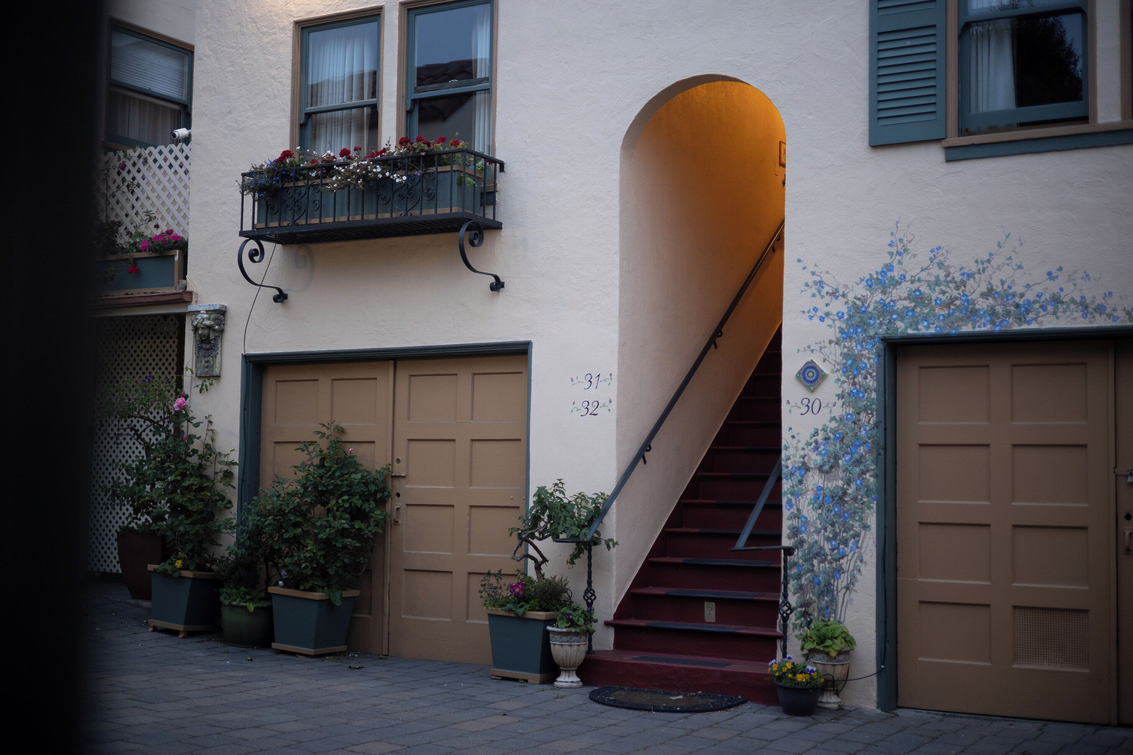 A building with a staircase leading to a second floor, potted plants, and a number '30' on the wall.