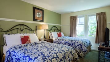 Habitación de hotel con dos camas, un cuadro en la pared, una ventana con cortinas y una mesita de noche con lámpara.