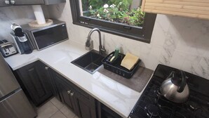 A compact kitchen with a sink, stove, and a window overlooking a garden. - Marina Motel (San Francisco)