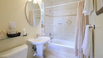 Un baño con bañera, lavamanos, espejo y cortina de ducha.