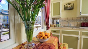 A kitchen with a window, a vase with flowers, and a bowl of oranges on a table. - Marina Motel (San Francisco)