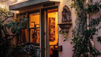 A building with a sign reading "OFFICE" at the entrance, potted plants, and a small statue outside.