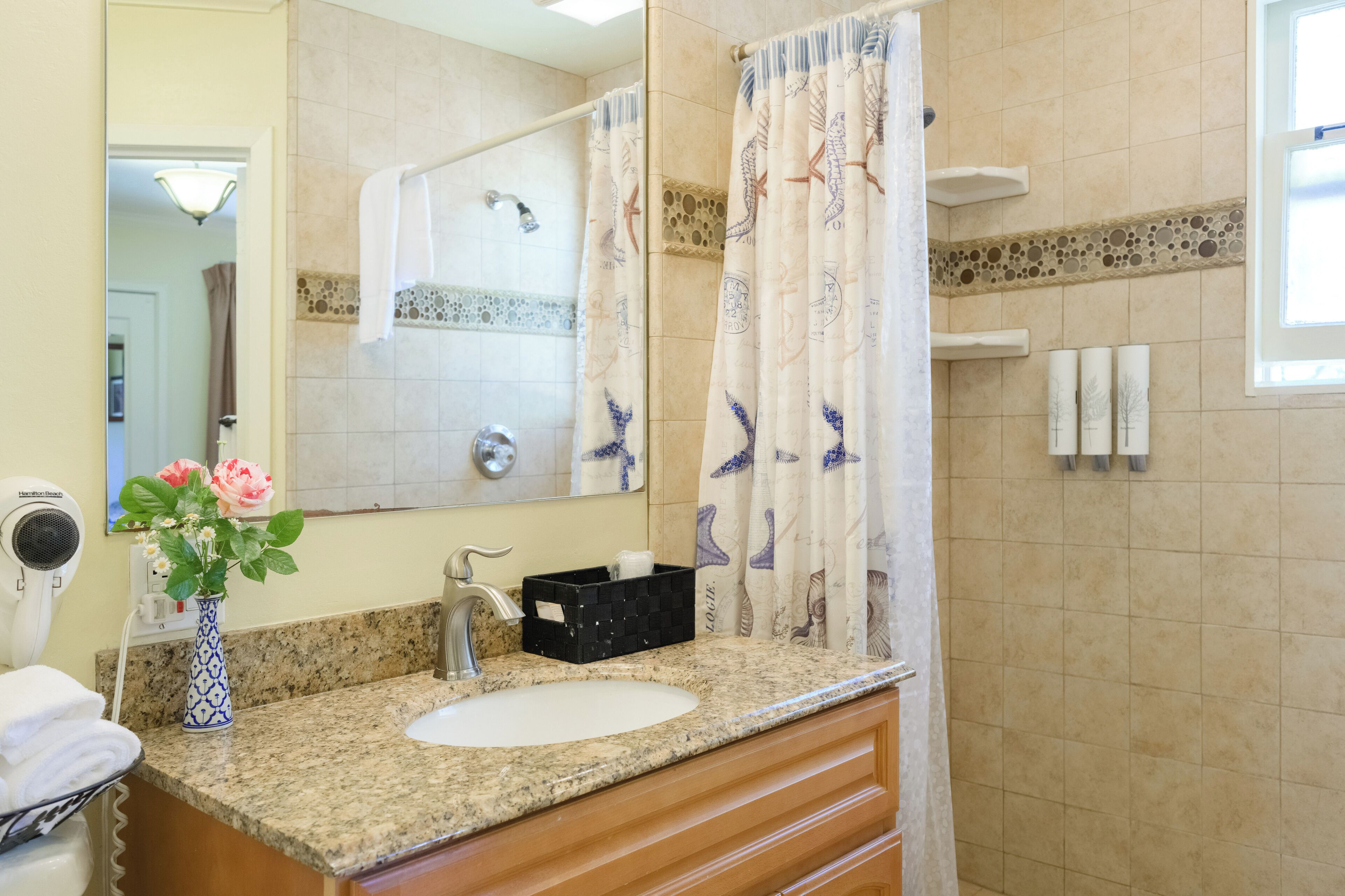 A bathroom with a sink, mirror, towel rack, and a shower curtain with a nautical theme.