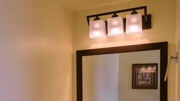 A bathroom with a white sink, dark vanity, and a mirror with three lights.
