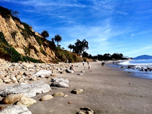 A rocky beach with people walking, palm trees, and a clear sky. - Coast Village Inn - Santa Barbara (Santa Barbara)