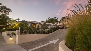 A coastal village inn with a paved driveway leading to the entrance, surrounded by greenery and a clear sky. - Coast Village Inn - Santa Barbara (Santa Barbara)