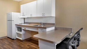 A compact kitchen with white cabinets, a built-in oven, a microwave, and a sink. - Extended Stay America Suites Toledo Holland (Holland)