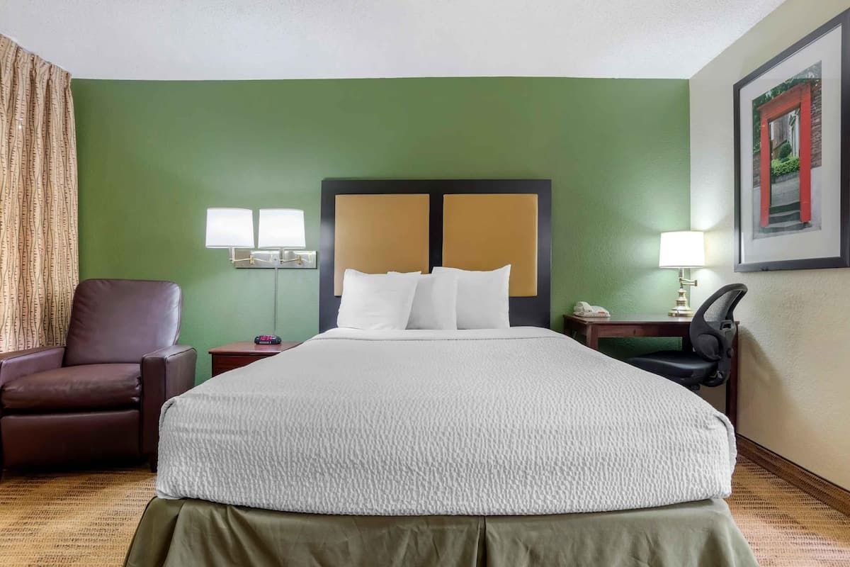 Une chambre d’hôtel avec un grand lit, une chaise, un bureau et une lampe.