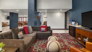 A spacious lobby with a sectional sofa, a flat-screen TV, and a patterned carpet.