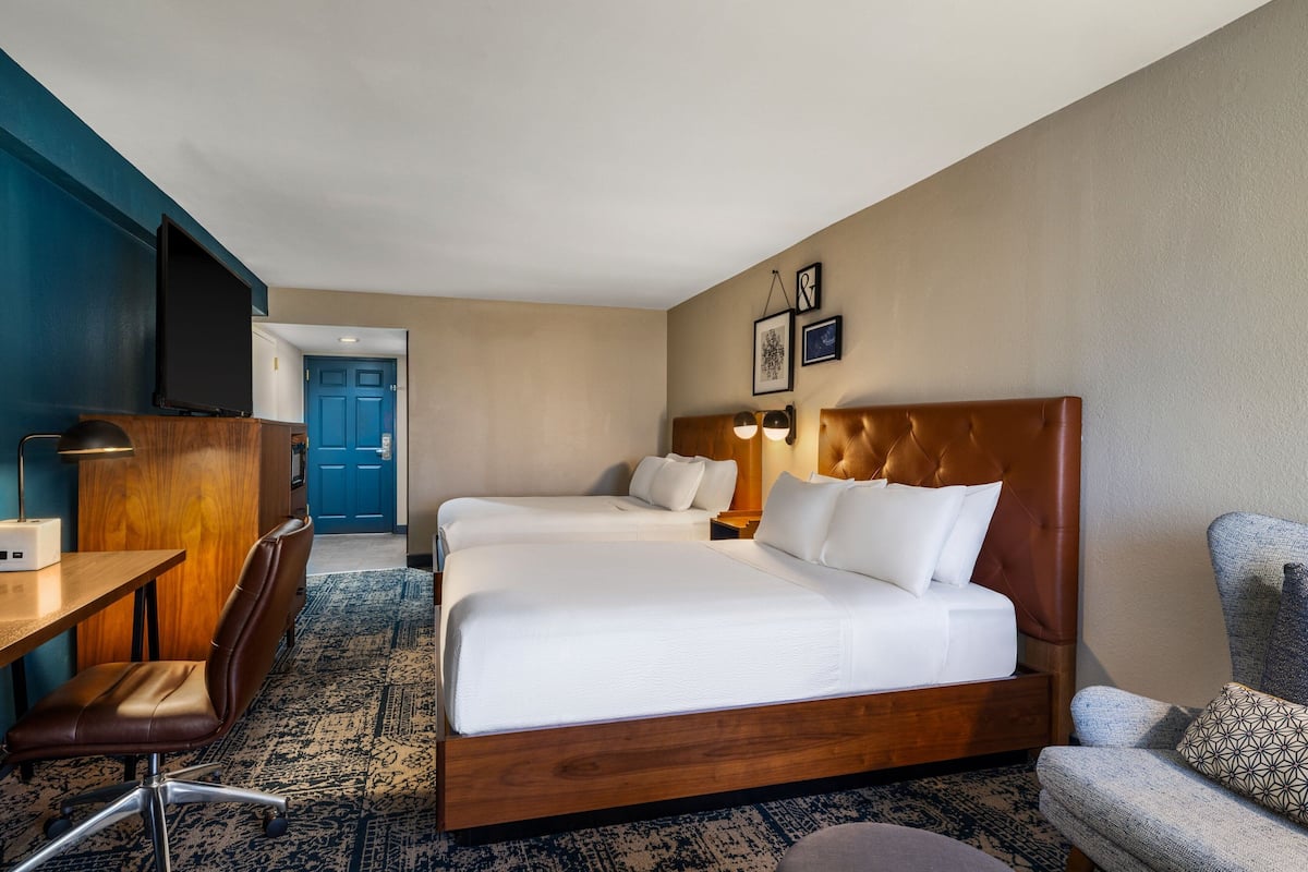 A hotel room with a large bed, a desk, a chair, and a television.