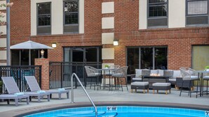 A swimming pool with lounge chairs and a fire pit area.