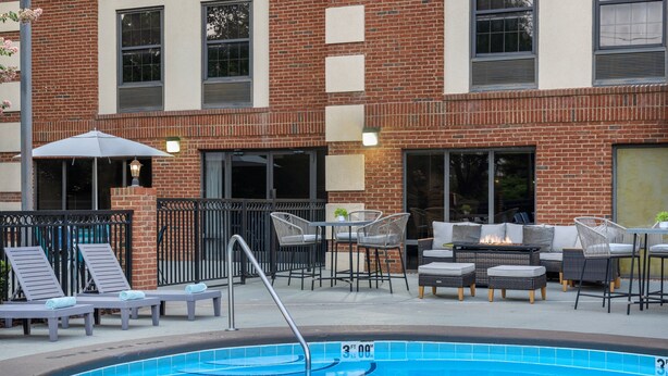 A swimming pool with lounge chairs and a fire pit area. - Four Points by Sheraton Greensboro Airport (Greensboro)