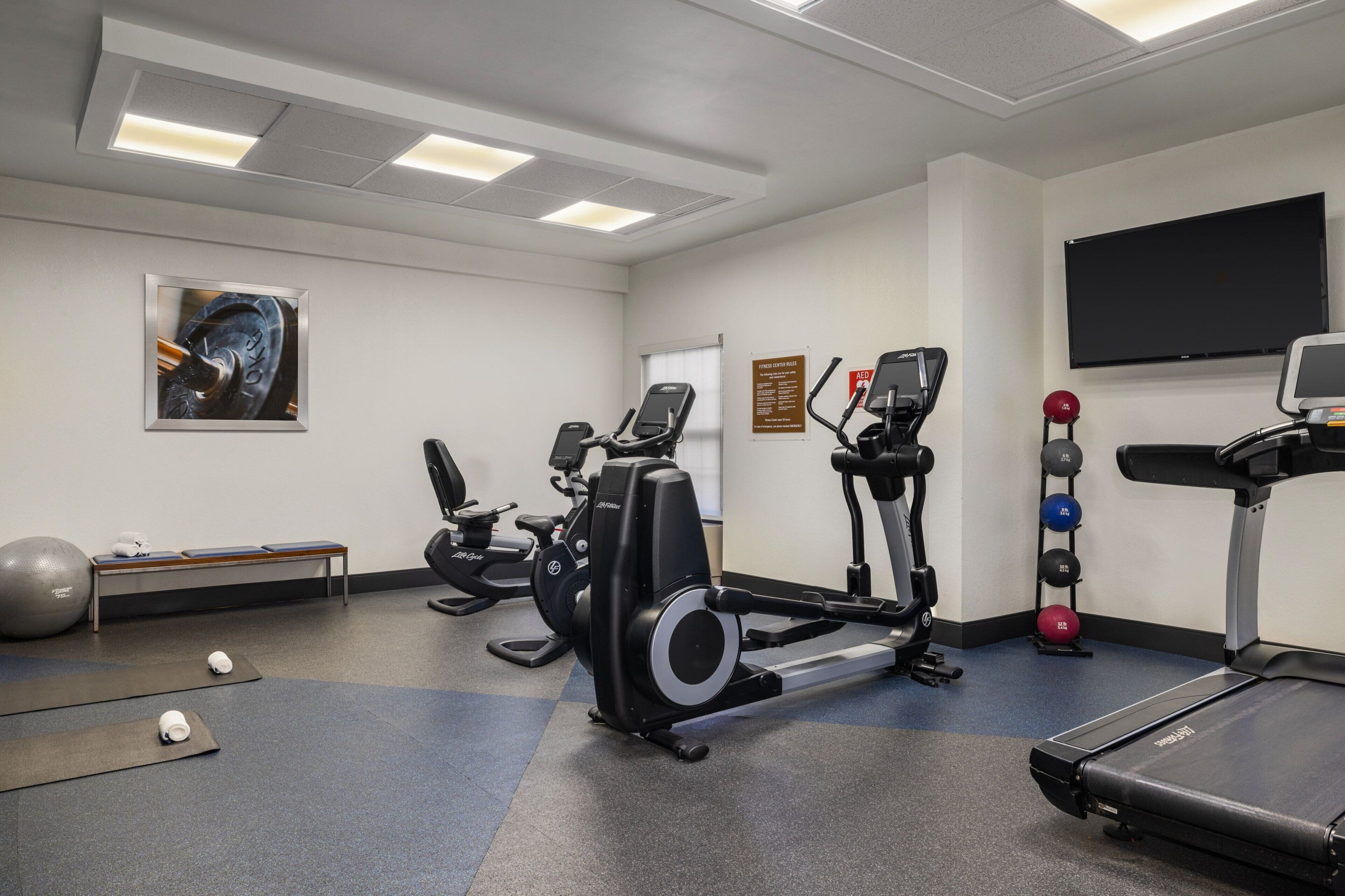 Een sportschool met trainingsapparatuur, een bank en een loopband.