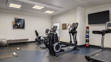 Un gimnasio con equipo de ejercicio, una banca y una cinta de correr.