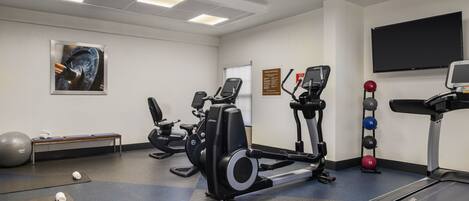 Een sportschool met trainingsapparatuur, een bank en een loopband.