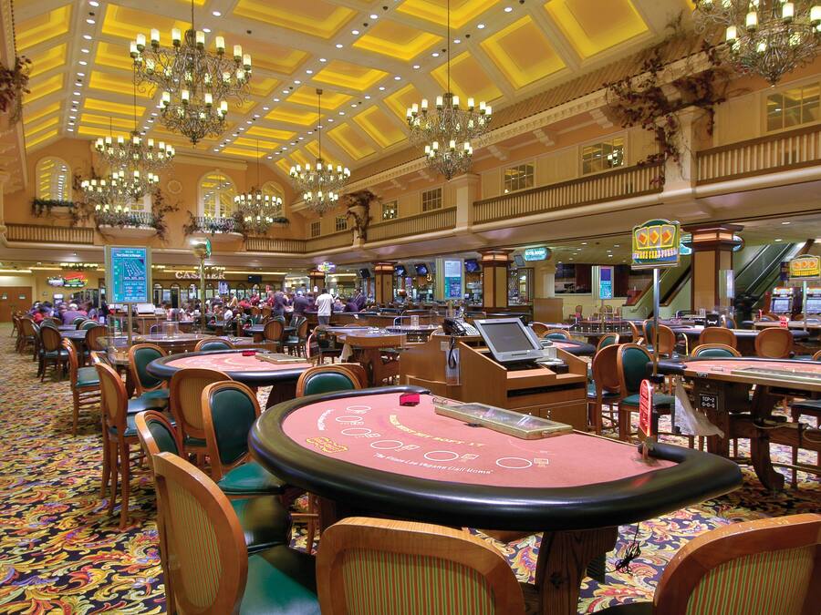 A spacious casino with multiple blackjack tables and a vibrant, patterned carpet.