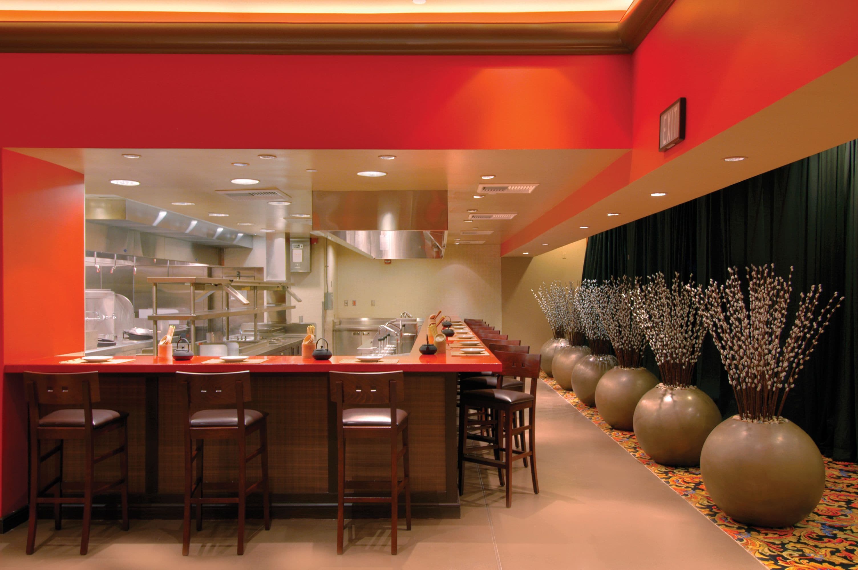 Una cocina moderna con una encimera larga, taburetes de bar y jarrones decorativos.