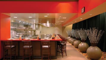 Una cocina moderna con una encimera larga, taburetes de bar y jarrones decorativos.