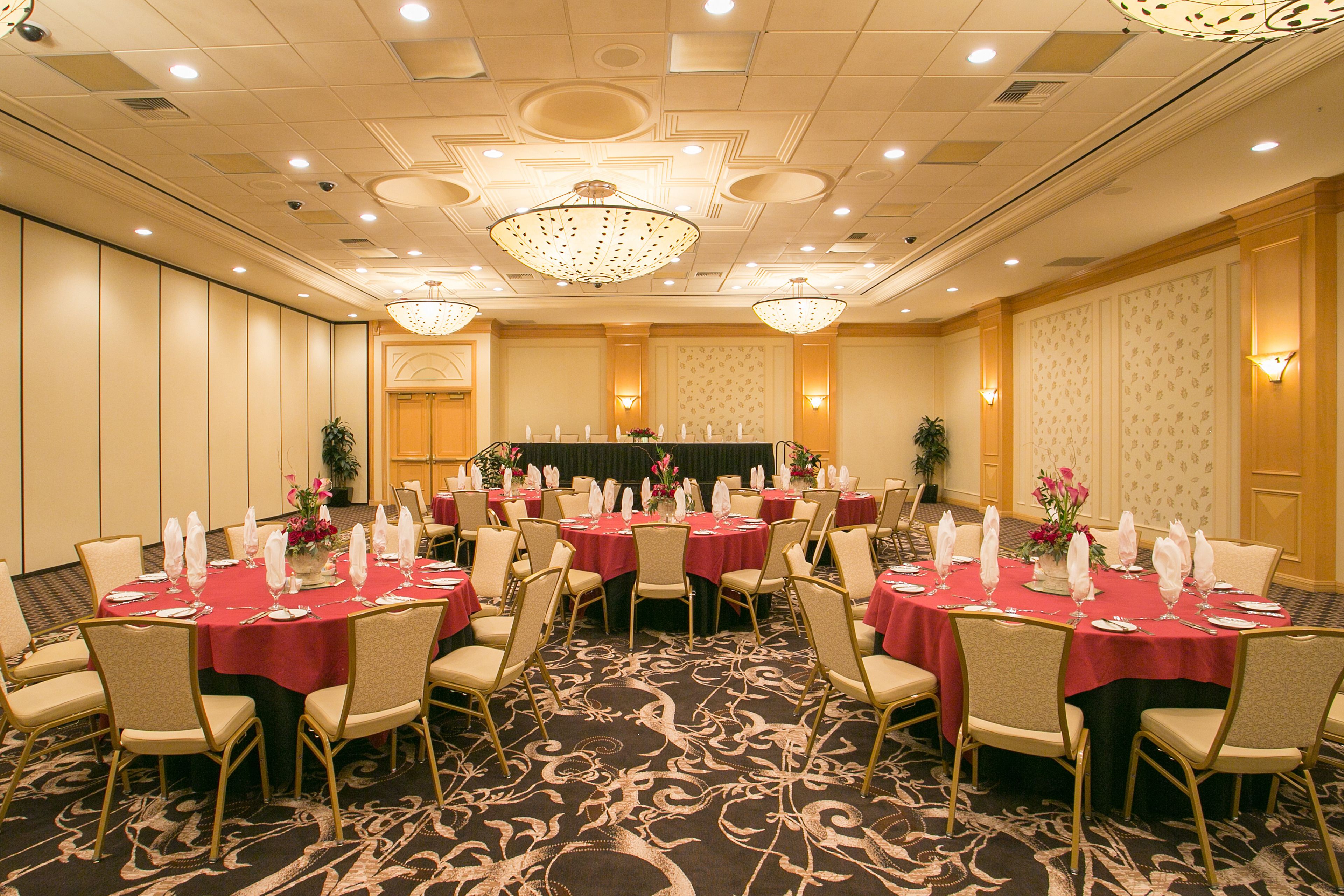 Une salle de banquet avec des tables rondes, des chaises et une scène.