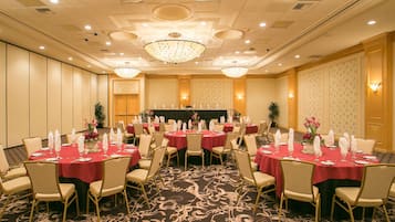 Une salle de banquet avec des tables rondes, des chaises et une scène.