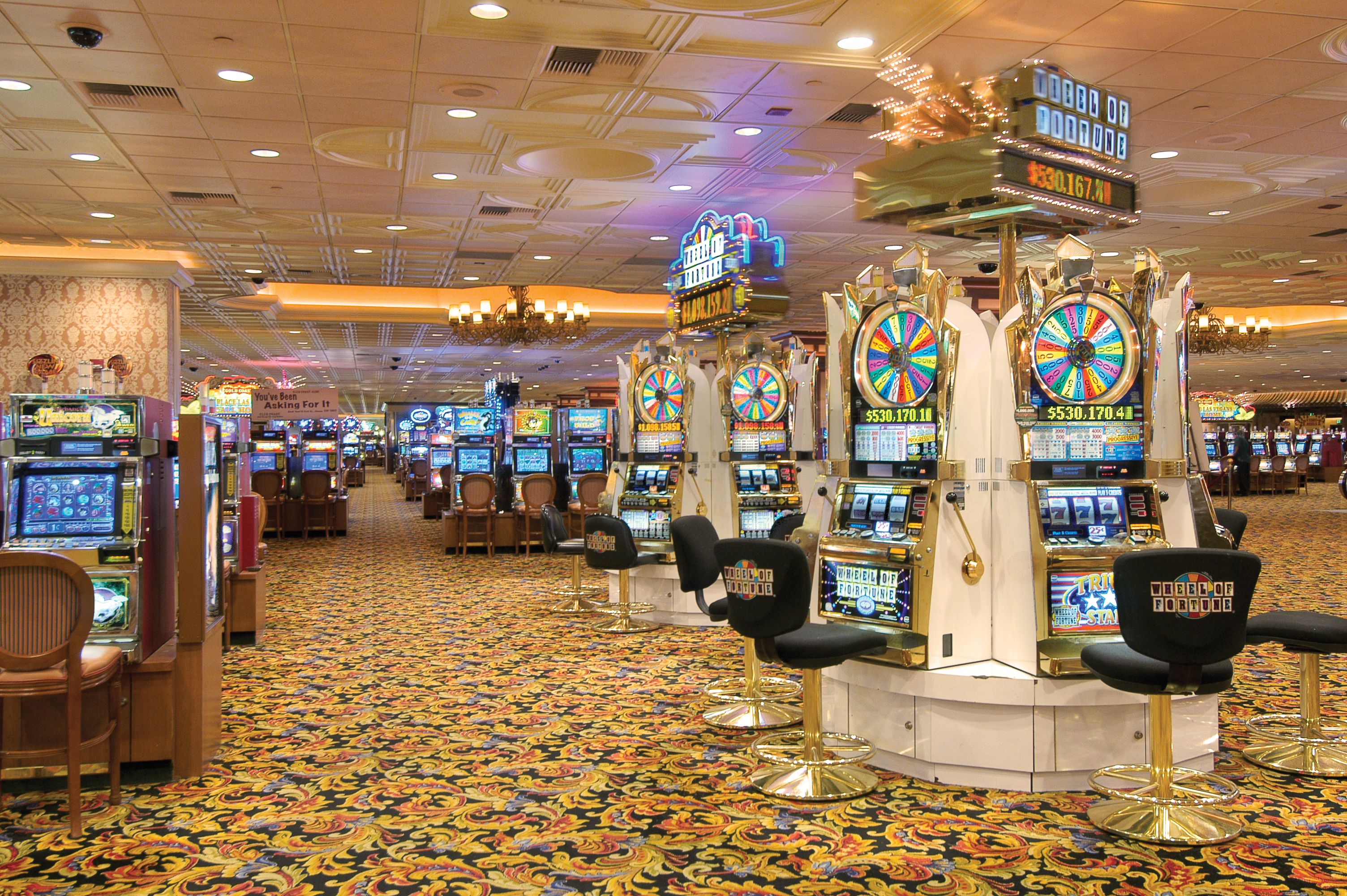 Un casino doté de nombreux jeux de machines à sous et dont le sol est recouvert de moquette.