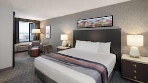 A hotel room with a large bed, two bedside tables with lamps, a chair, a small table, and a window with curtains. - Gold Coast Hotel and Casino (Las Vegas)