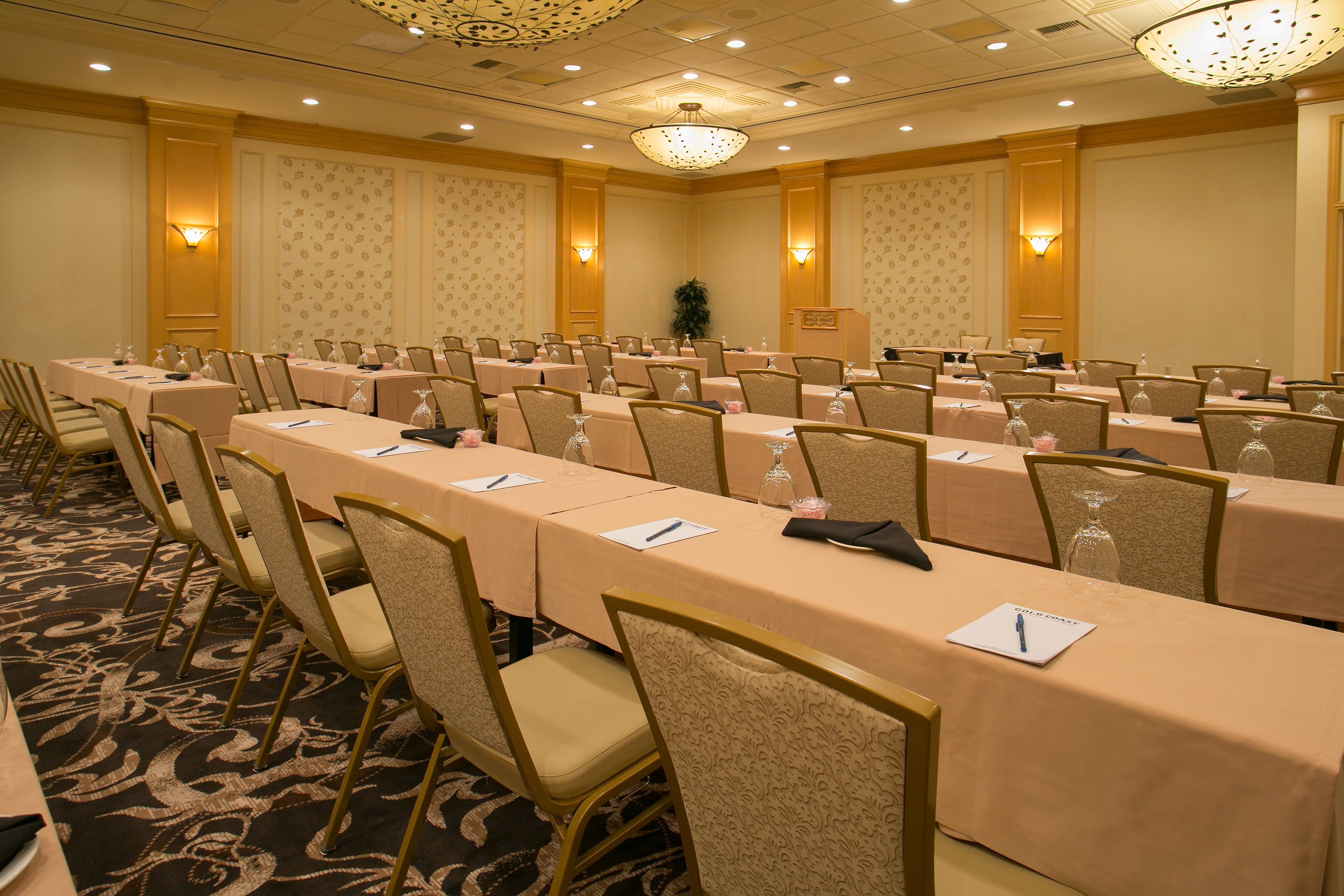 Une salle de conférence équipée de longues tables, de chaises et d’un pupitre.