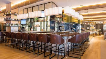 A bar area with multiple stools, a bar counter, and shelves stocked with bottles.
