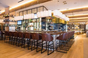 Eine Bar mit mehreren Barhocker, einer Theke und Regalen voller Flaschen.