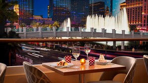 A dining table with chairs, a plate of food, and two wine glasses. - The Vanderpump Las Vegas Hotel Casino - A Caesars Rewards Destination (Las Vegas)