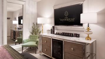 Une chambre d’hôtel avec un lit, un fauteuil vert, une console sur laquelle se trouve un téléviseur et un miroir.