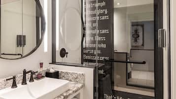 A modern bathroom with a large mirror, a sink, and a glass shower enclosure.