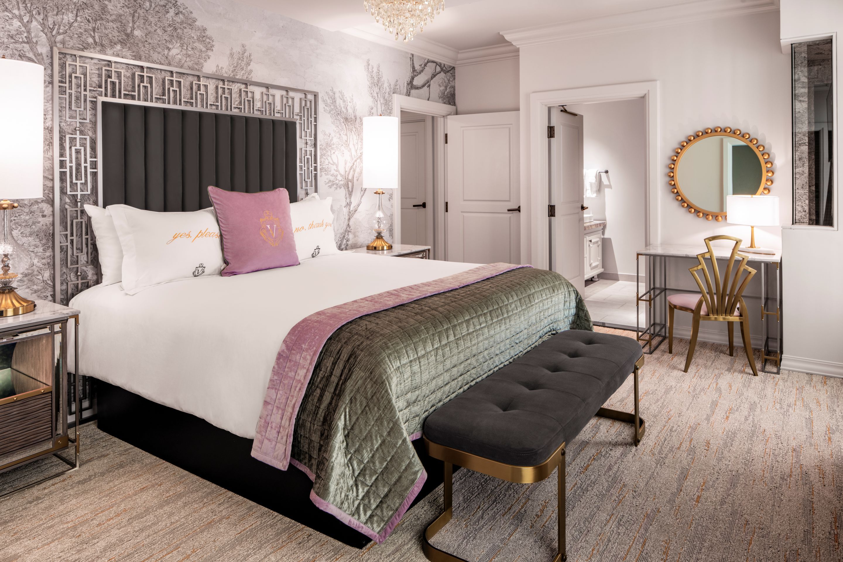 Une chambre à coucher avec un grand lit, des tables de chevet, un banc, un bureau et un miroir.