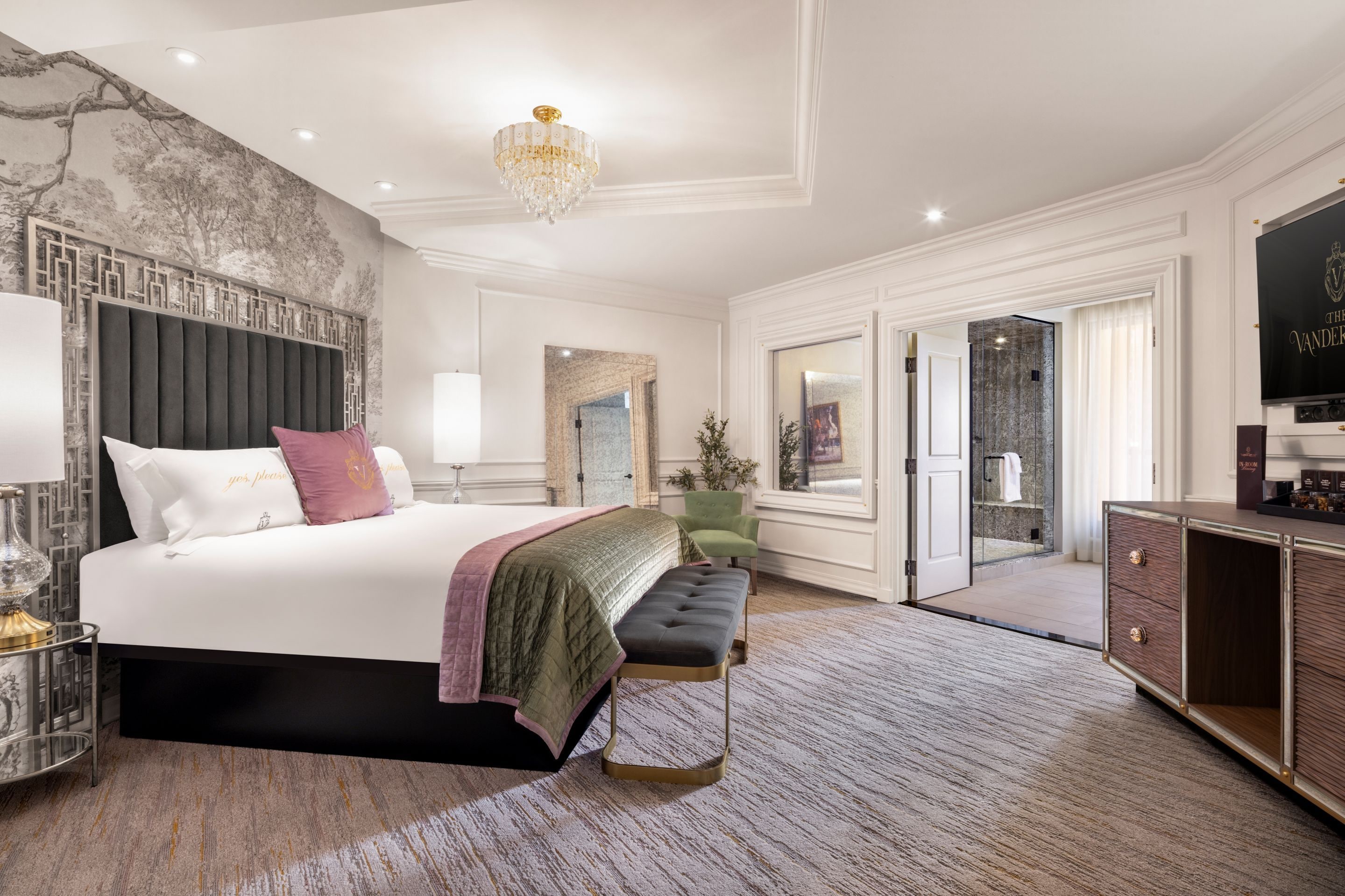 A spacious bedroom with a large bed, a sitting area, a vanity, and a walk-in closet.